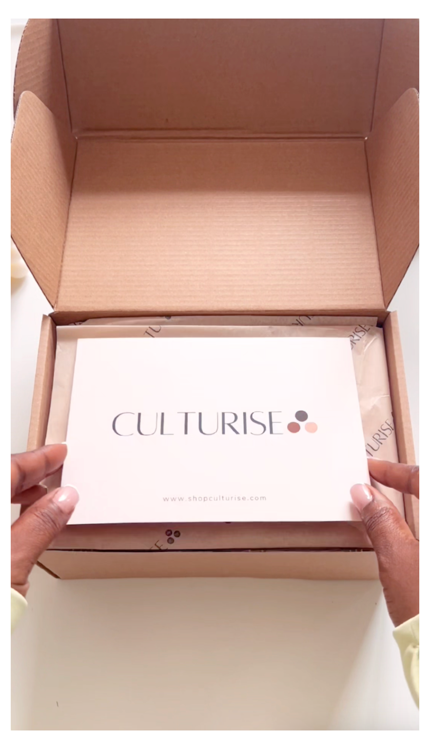 Open cardboard box with a Culturise product inside, held by hands.